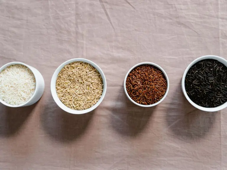 White, brown, red and black rice in white bowls